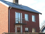 Helglasad dubbeldörr och fyra grö fönster med naturanodiserade aluminiumbleck H-Fönstret